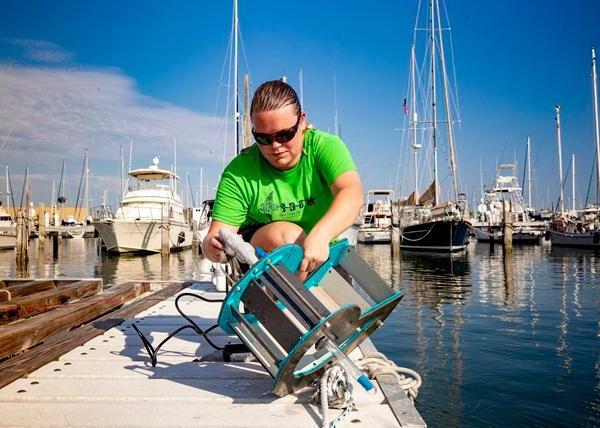 An oceanography student works with a testing device at the marina